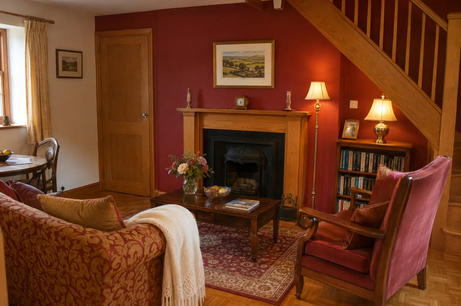 Cosy sitting room with a fireplace, sofa, bookshelves and staircase